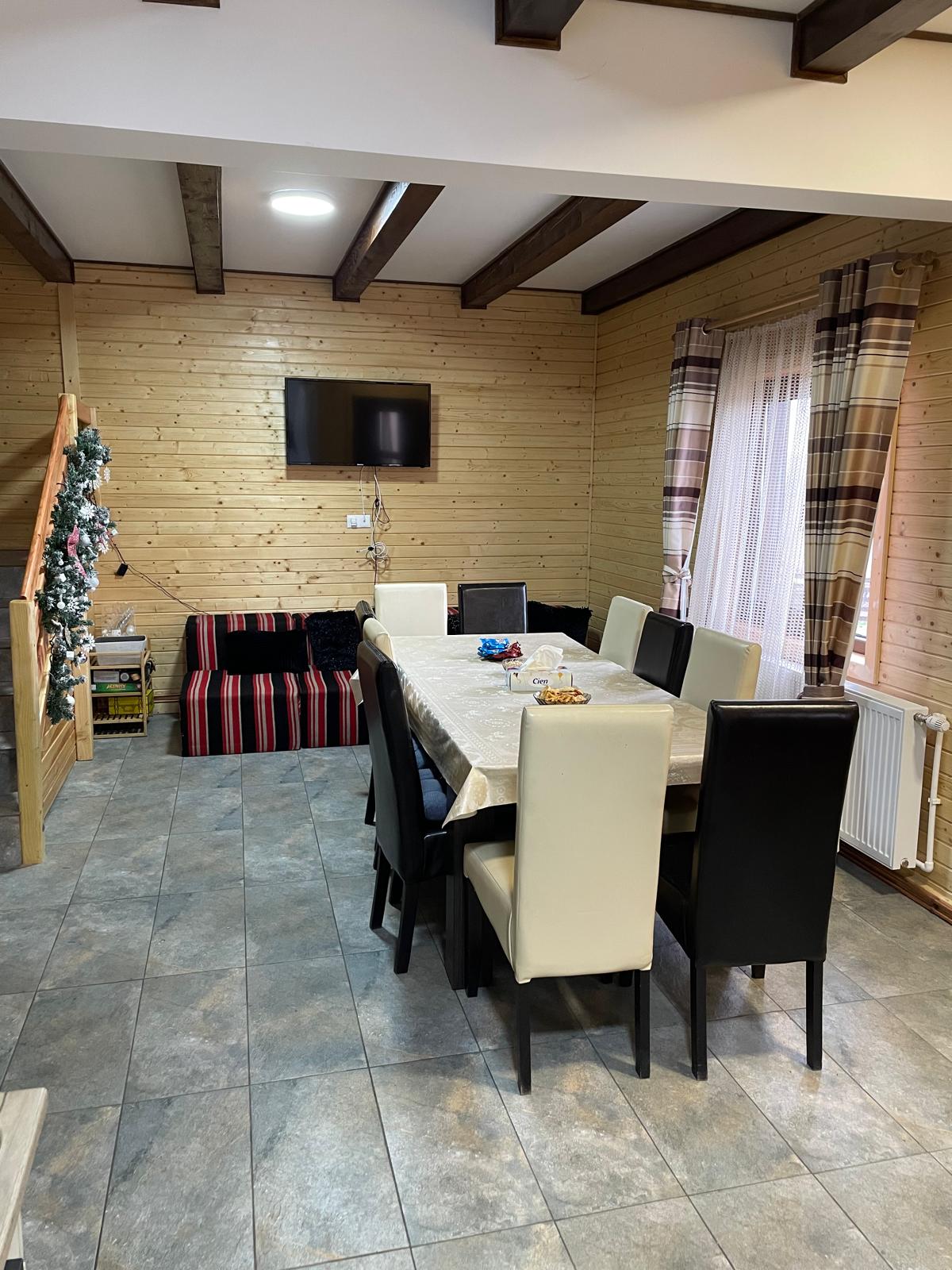 Living cu masă mare, canapea și TV